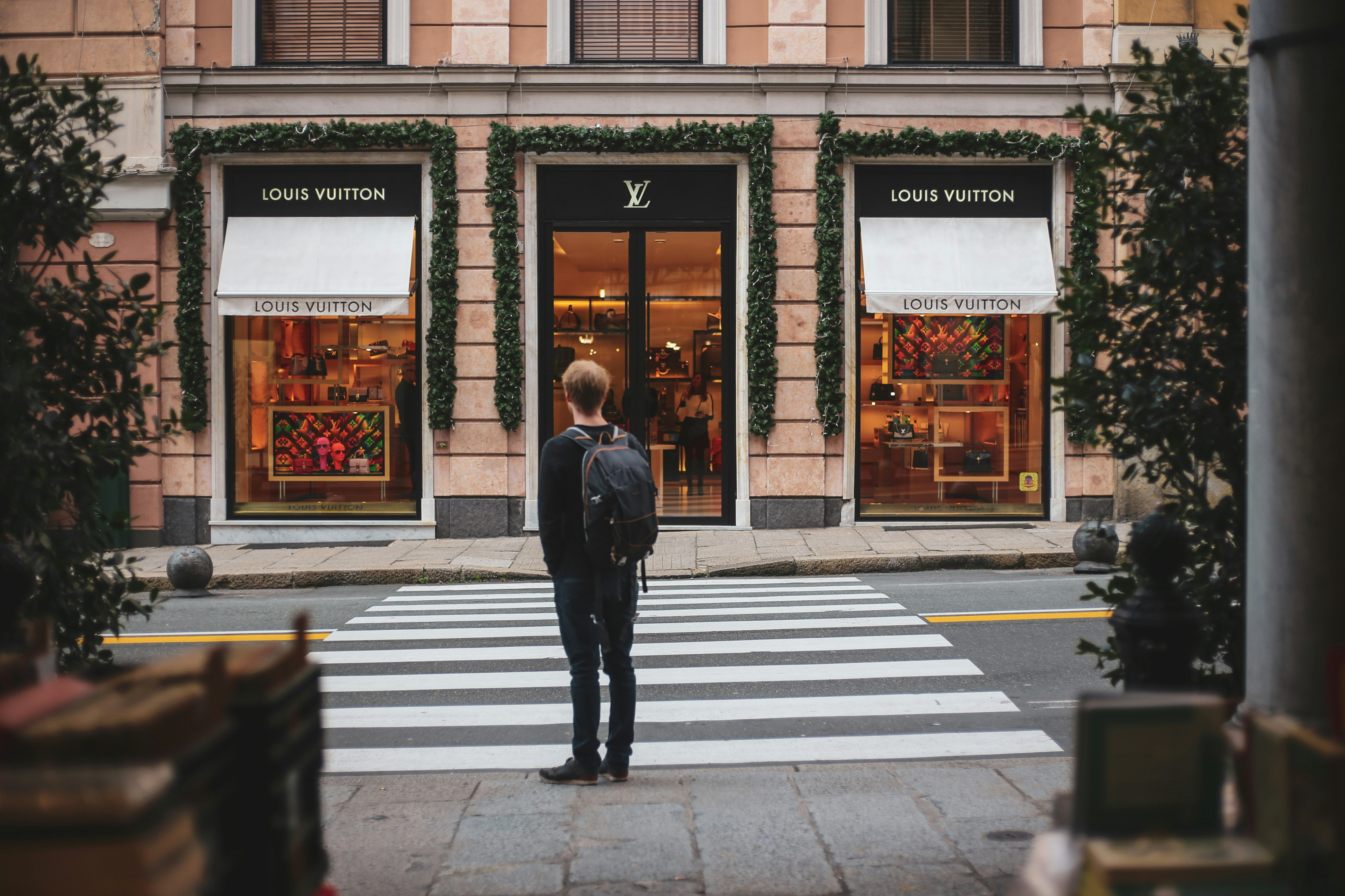 Person standing in front of a luxury Louis Vuitton storefront, representing premium branding and unforgettable visual identity.