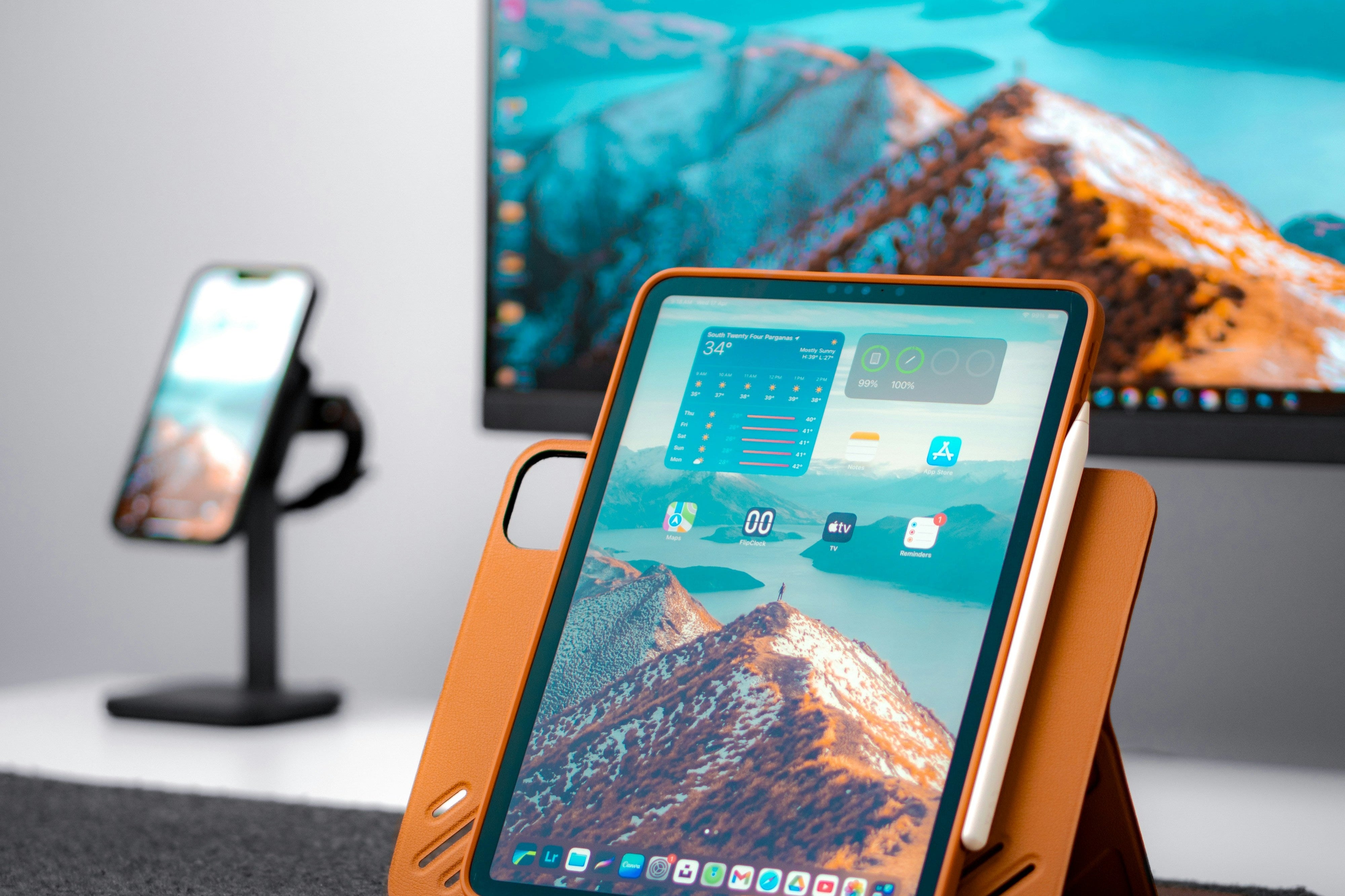 A sleek setup featuring a tablet with a vibrant mountain-themed display, a smartphone on a stand, and a background monitor, showcasing cutting-edge technology and productivity tools.