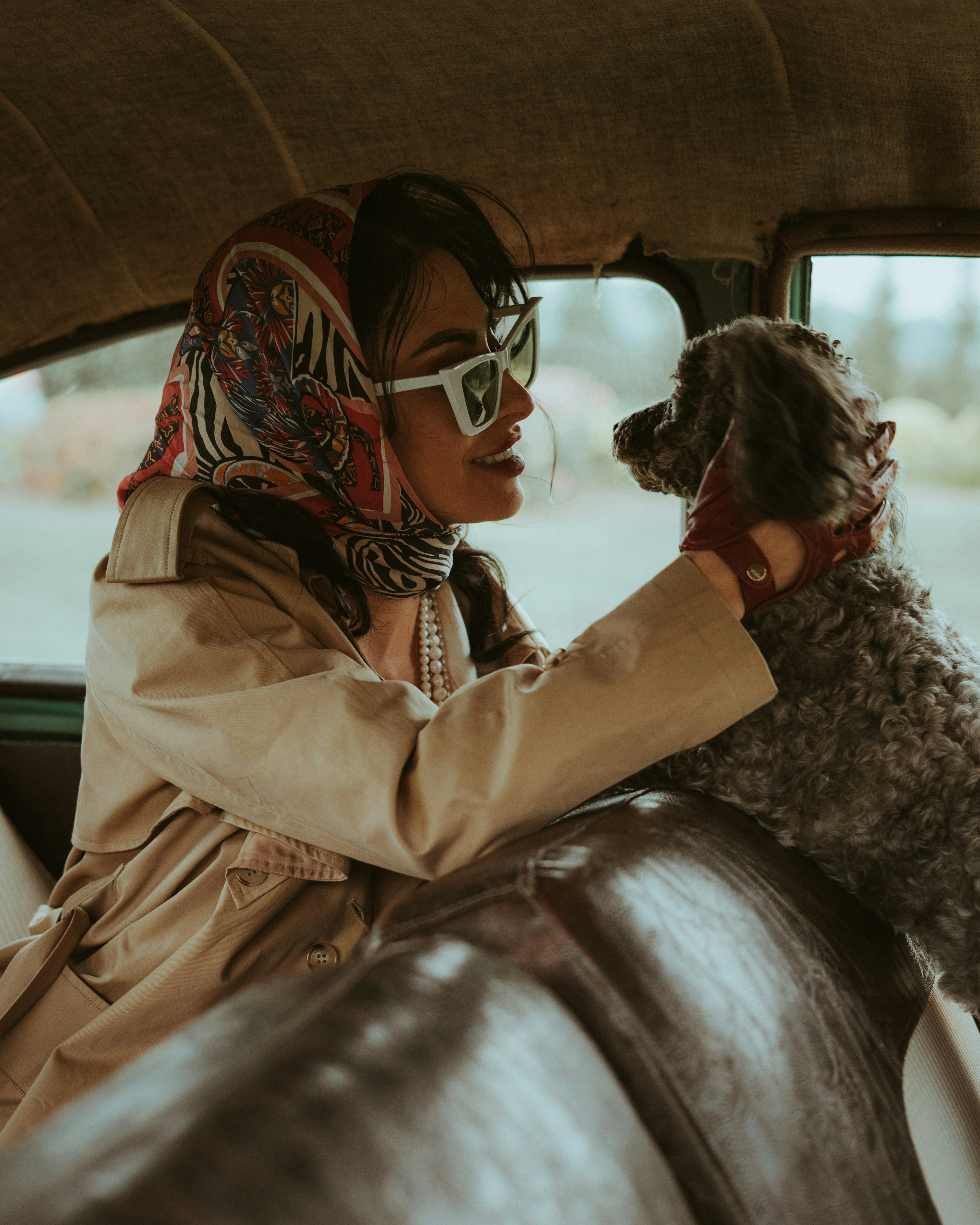 Stylish woman in a classic car with her dog, symbolizing luxury and boosting brand identity.