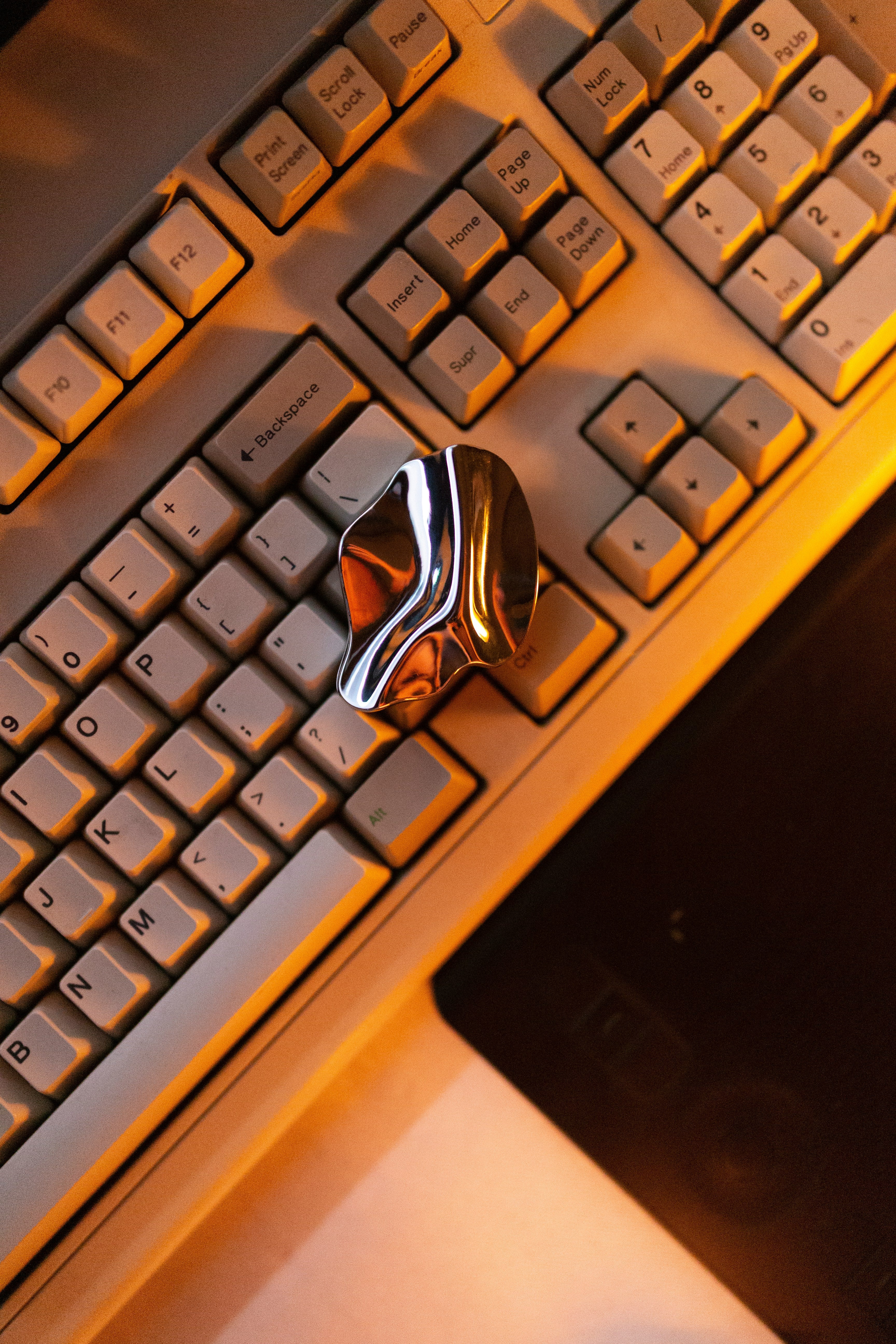 Sleek metallic sculpture placed on a keyboard, representing innovation in digital marketing.